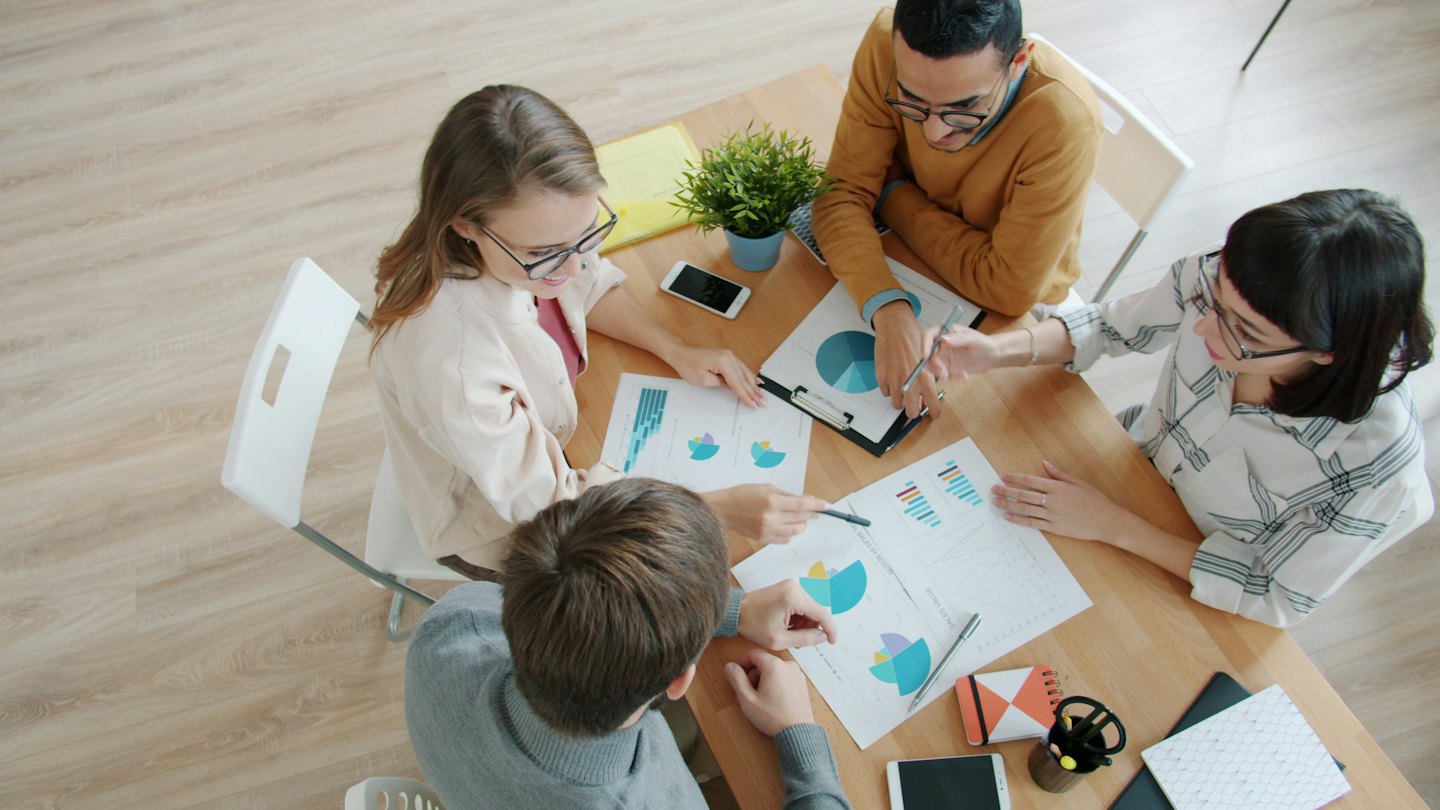 Team eterogeneo collabora su grafici finanziari a un tavolo.